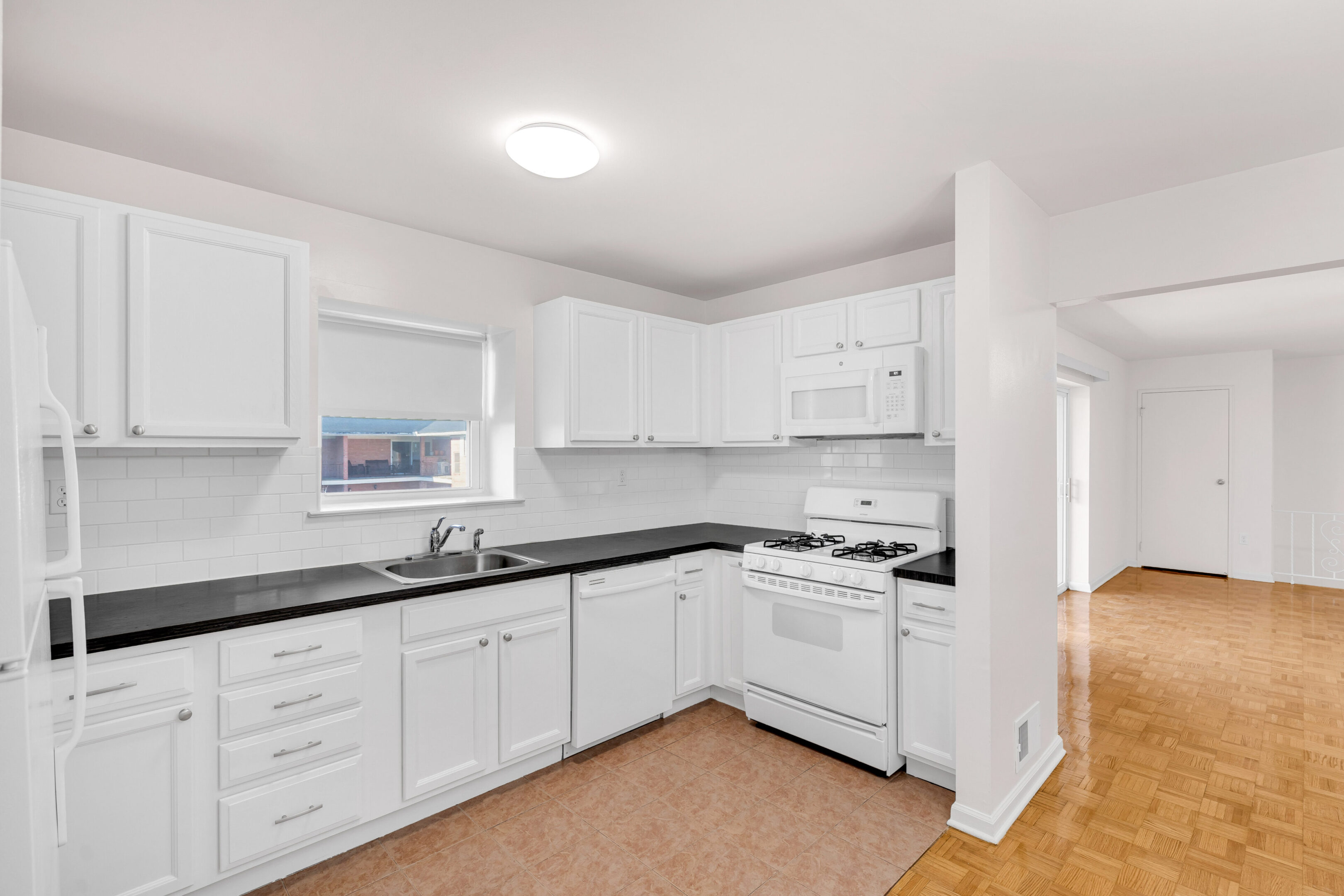 A kitchen with white cabinets and black counter tops.