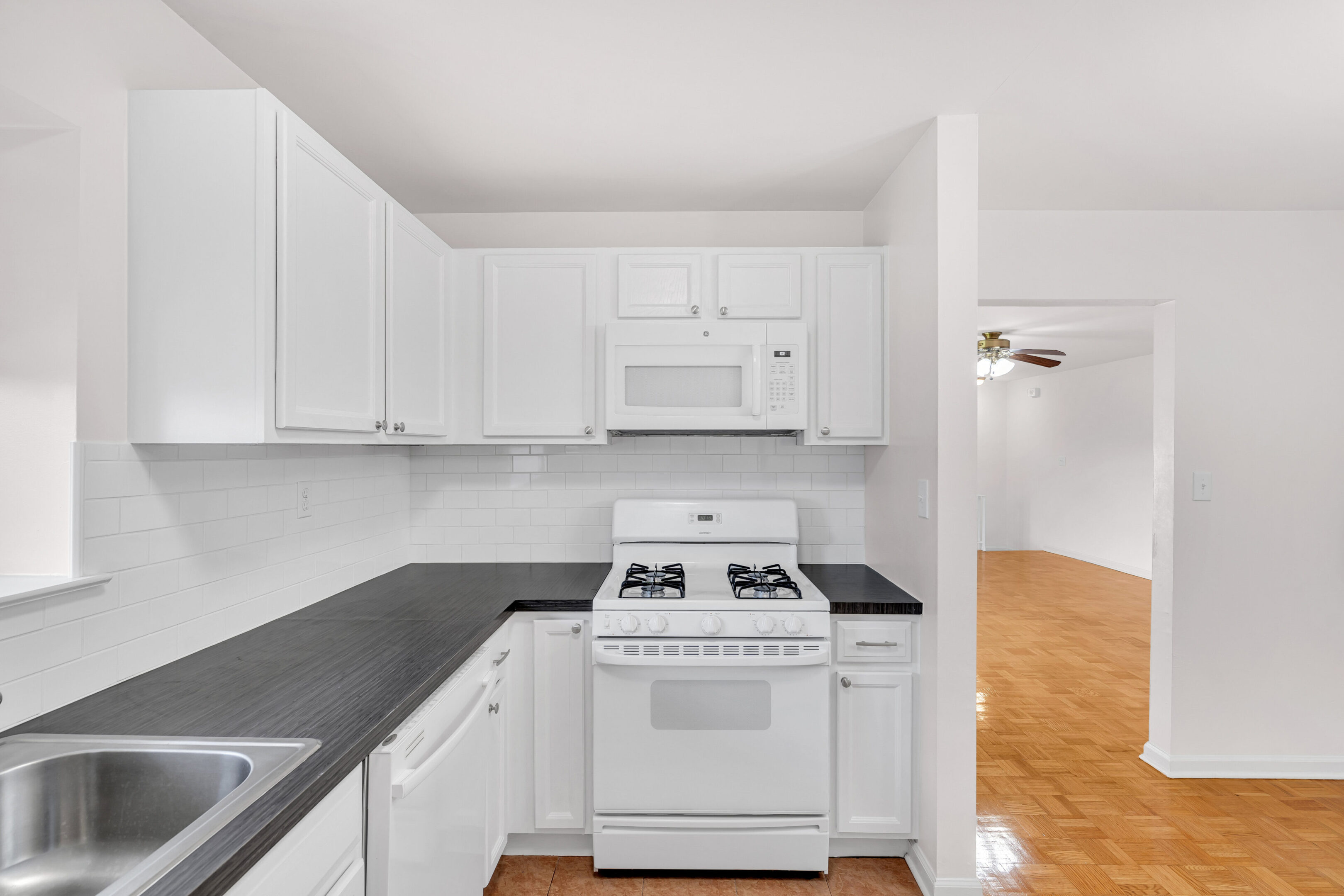 A kitchen with white cabinets and black counter tops.