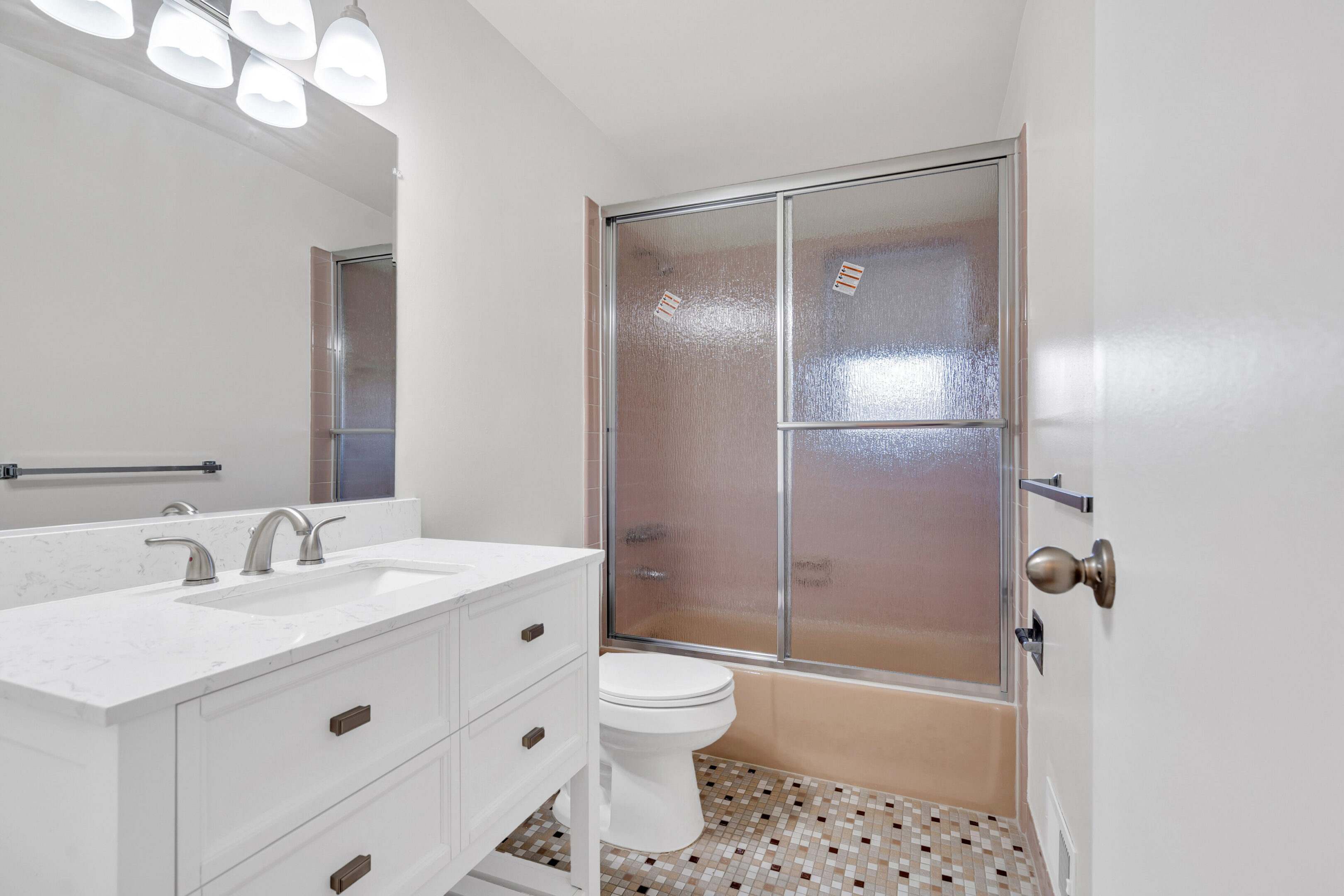 A bathroom with white cabinets and tile floors.