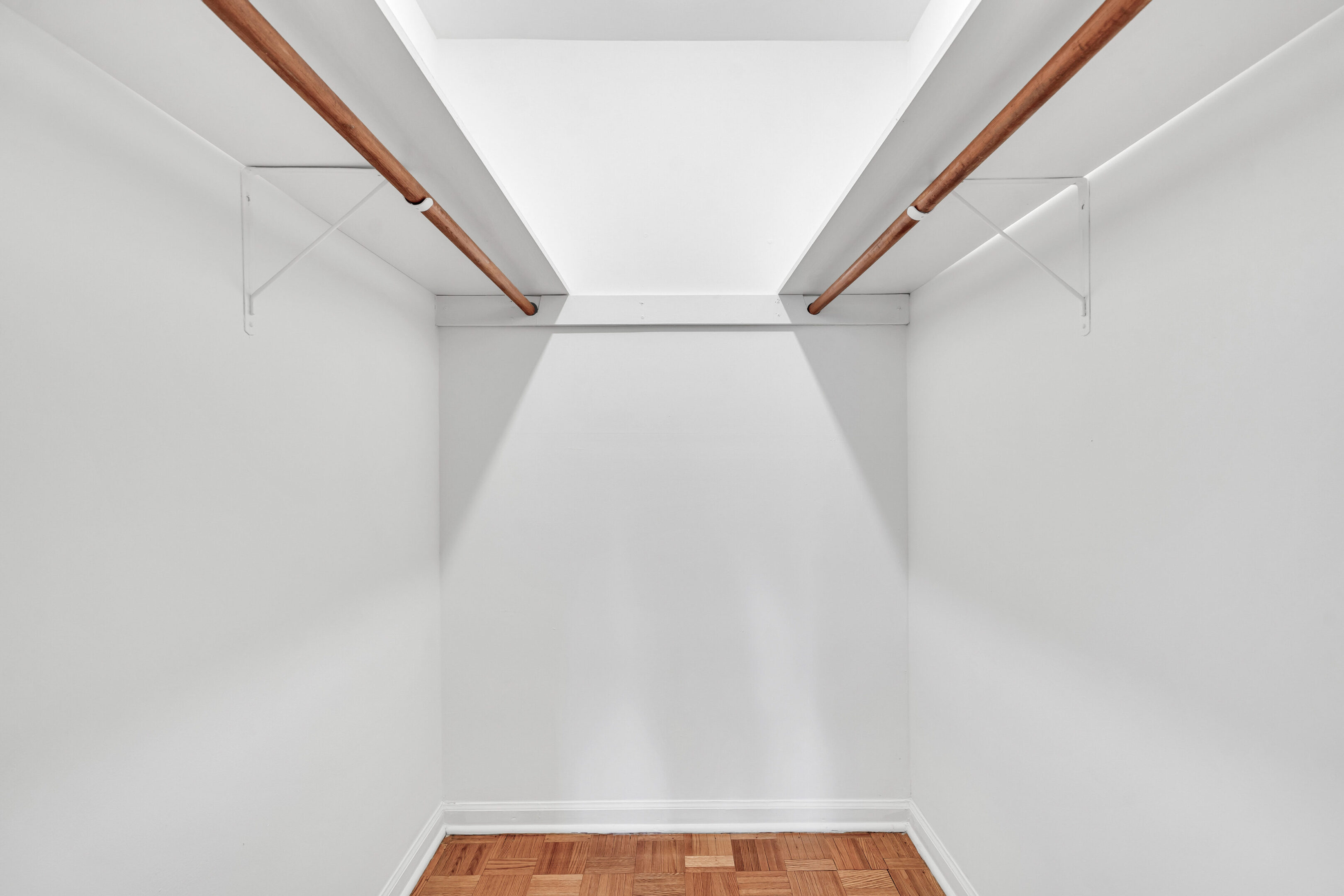 A white room with wooden floors and two closets.