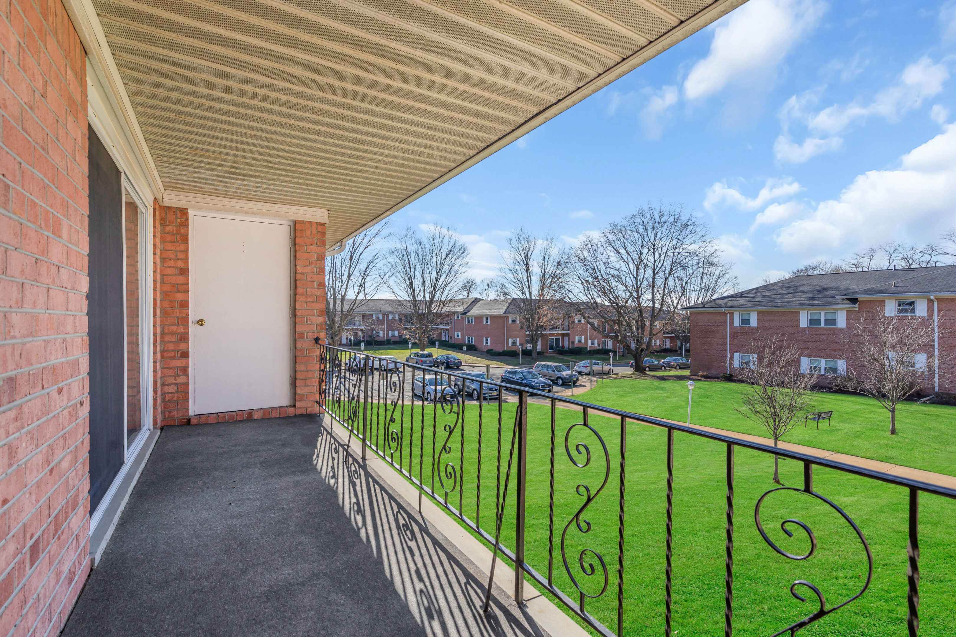 A balcony with a fence and grass on the side.