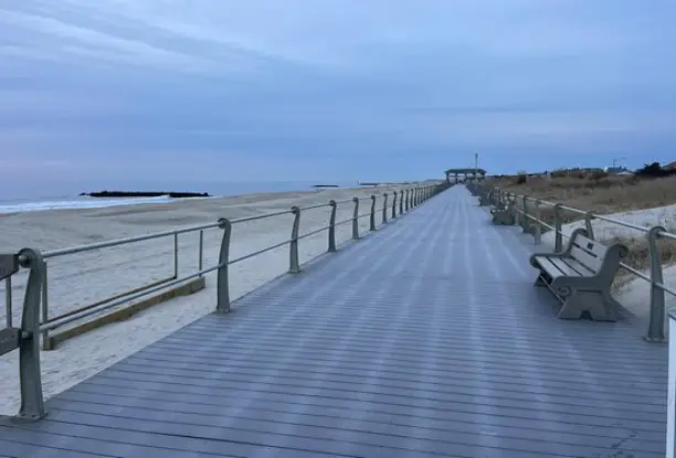 A boardwalk with benches and railing along the edge of the beach.