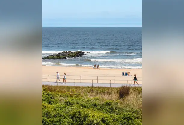 A beach with people walking on it and the ocean in the background.