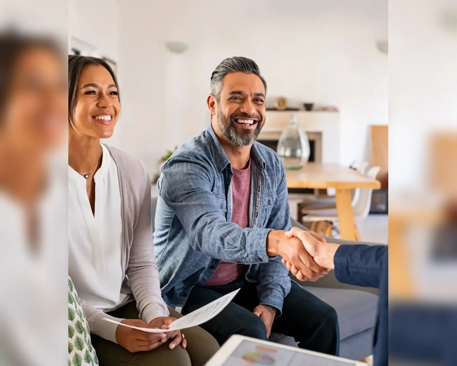 A man and woman shaking hands while sitting on the couch.