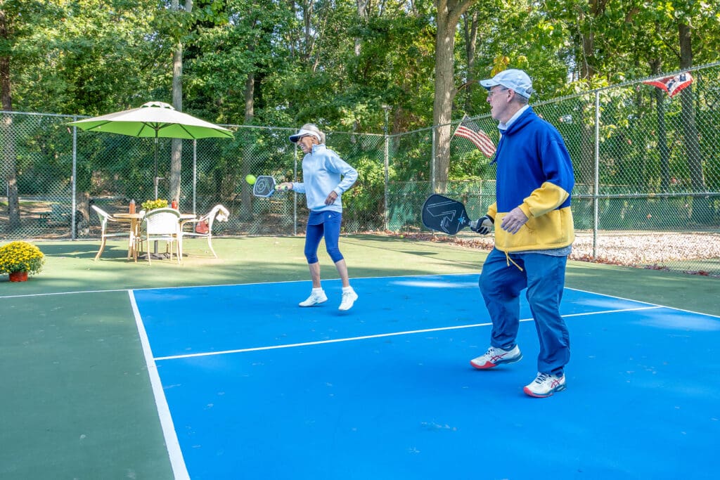 Two people playing tennis on a blue court.