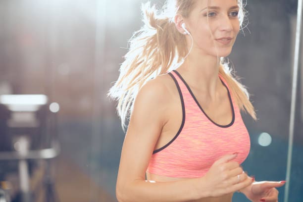 A woman running in the gym wearing pink